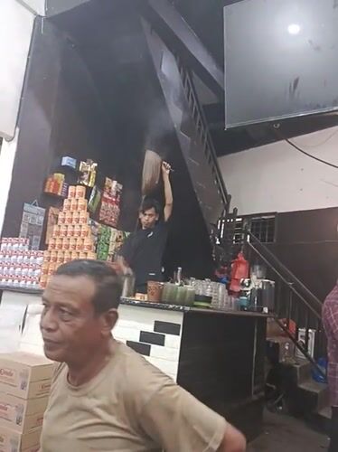 Man smokes cigarette inside small store in Kruet Teumpeun