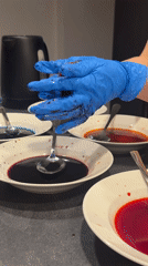 Person arranges colorful liquids on plates in Gudauri