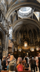 Tourists visit cathedral in Monistrol de Montserrat, light votive candles