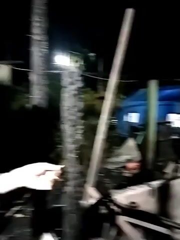 The video shows the aftermath of a fire. The structure of a building remains, but it's severely damaged with charred materials. A blue tent is visible in the background. It is dark outside. No people are visible.