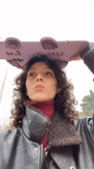 Woman holds pink skateboard overhead in Pardes Hana-Karkur
