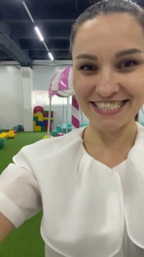 Woman films, dances at Russian playground while child rides carousel