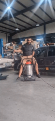 Man rides industrial vacuum like horse in garage