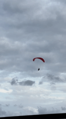 Red paraglider spotted against overcast sky