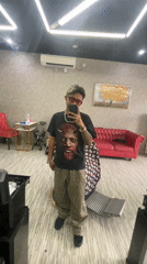 Young adult takes mirror selfie in Kuta barbershop