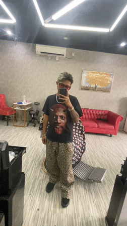 Young adult takes mirror selfie in Kuta barbershop