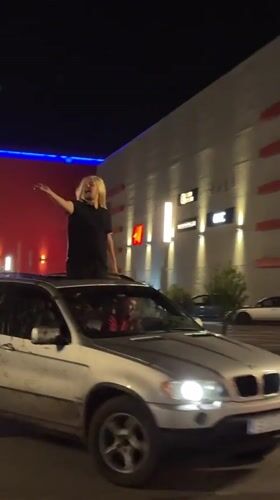 Woman waves from BMW sunroof in Ruse parking lot