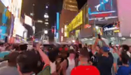 Nighttime crowd gathering in Times Square's bright billboard district