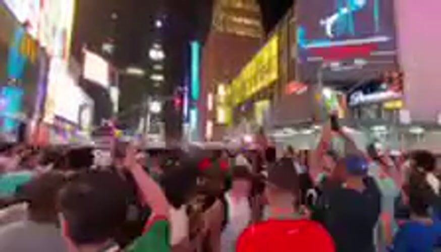 Nighttime crowd gathering in Times Square's bright billboard district