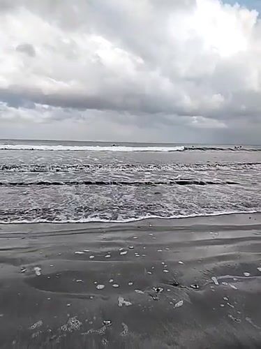 Busy surf session at Kuta Beach on an overcast morning