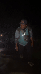 Nighttime group with flashlights walks wooded path in Indonesia