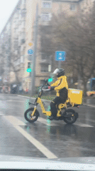 Delivery scooter navigates rainy Moscow intersection during morning hours