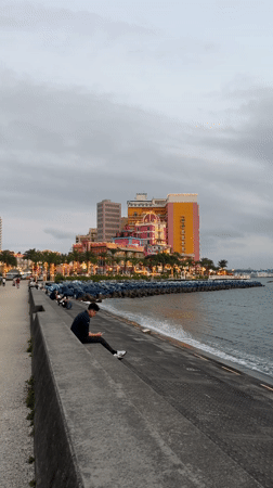 Person uses phone at Chatan waterfront ledge