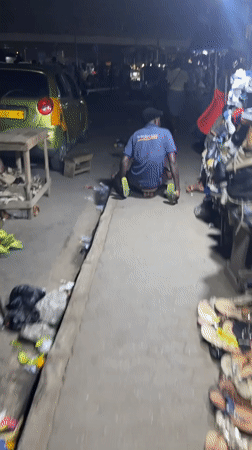 Man navigates nighttime street market in Accra, Ghana