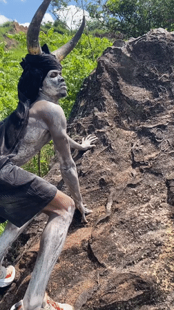 Horned performer in body paint climbs rock in Nigeria