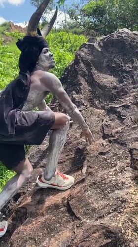 Horned performer in body paint climbs rock in Nigeria