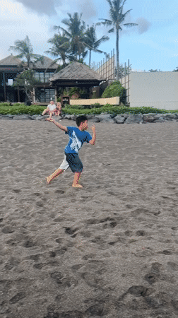 Beachgoers spotted on dark sand in Mengwi, Indonesia