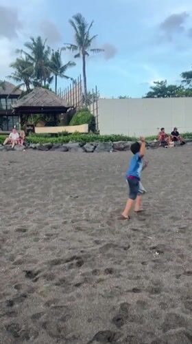 Beachgoers spotted on dark sand in Mengwi, Indonesia