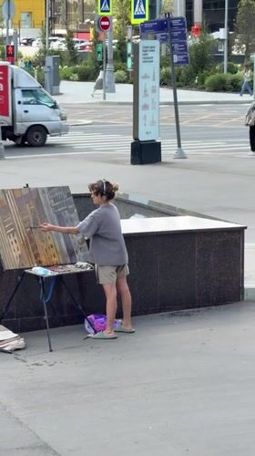 Artist paints urban landscape on a Moscow sidewalk