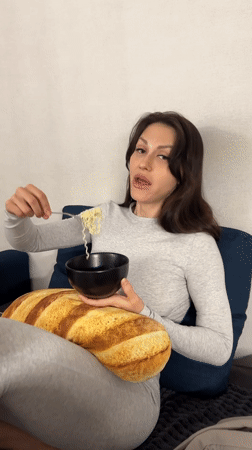 Woman enjoys noodle dinner on couch in Murino, Russia