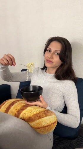 Woman enjoys noodle dinner on couch in Murino, Russia