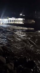 Nighttime river scene by a lit venue in Dushanbe