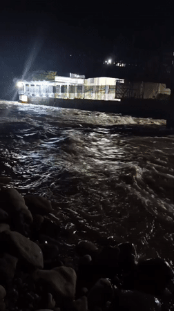 Nighttime river scene by a lit venue in Dushanbe
