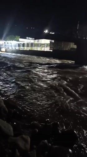 Nighttime river scene by a lit venue in Dushanbe