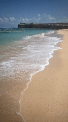 Calm beach day in Kuta Selatan with boats and bathers