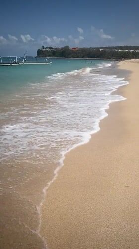 Calm beach day in Kuta Selatan with boats and bathers
