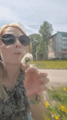 Woman blows dandelion near baby in stroller, Sterlitamak