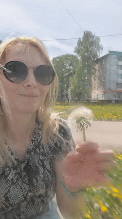 Woman blows dandelion near baby in stroller, Sterlitamak
