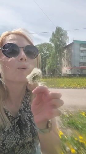 Woman blows dandelion near baby in stroller, Sterlitamak