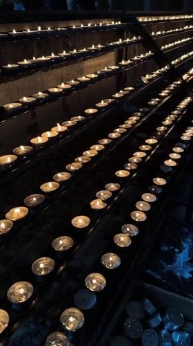 Woman lights prayer candle in Vienna cathedral