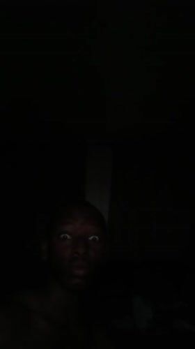 Person photographed in darkness with illuminated face in Lagos