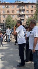 Group gathers on Yerevan sidewalk, man speaks into microphone