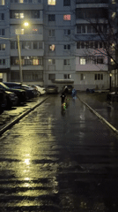 Child plays with scooter on wet evening street in Chaikovsky