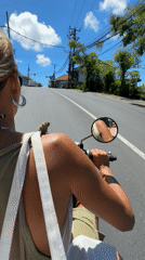 Woman rides scooter through Kuta Selatan on sunny morning
