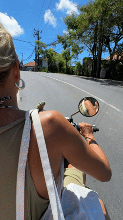 Woman rides scooter through Kuta Selatan on sunny morning