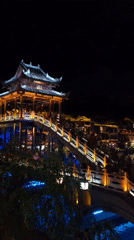 Fenghuang's Rainbow Bridge and riverfront glowing on a summer night