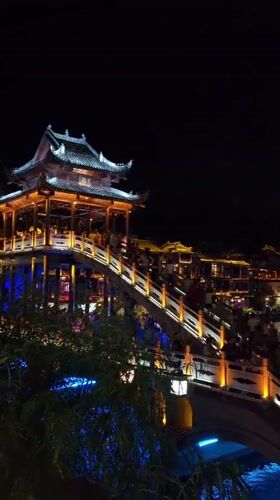 Fenghuang's Rainbow Bridge and riverfront glowing on a summer night