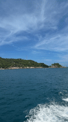 Boat approaches lush Ko Tao island under clear skies