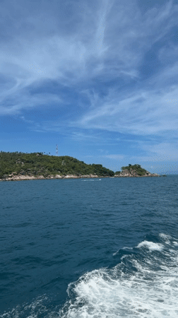 Boat approaches lush Ko Tao island under clear skies