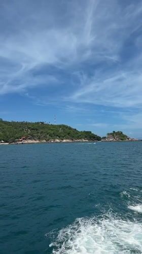 Boat approaches lush Ko Tao island under clear skies