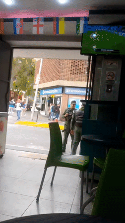 Street-level Caracas activity near Av. Bolívar, armed guard at pharmacy