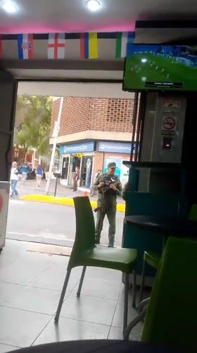 Street-level Caracas activity near Av. Bolívar, armed guard at pharmacy