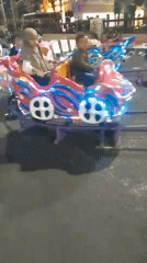 Neon-lit kiddie car carousel running at night in Jember