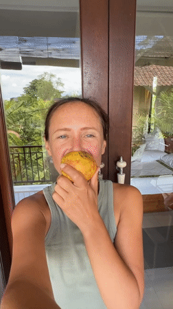 Woman displays red fruit near balcony in Ubud, Indonesia