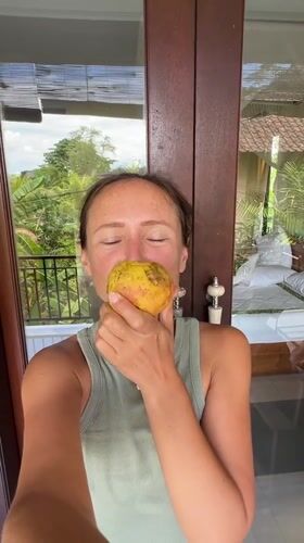Woman displays red fruit near balcony in Ubud, Indonesia