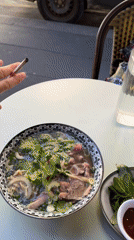 Woman enjoys Vietnamese pho at outdoor Paris cafe